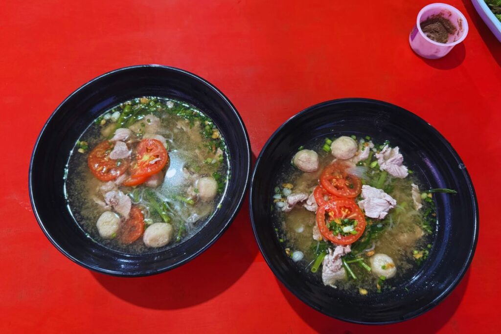 two noodle dishes on a red table