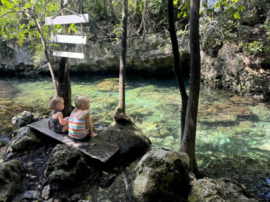 two girls sitting on the edge of a cenote