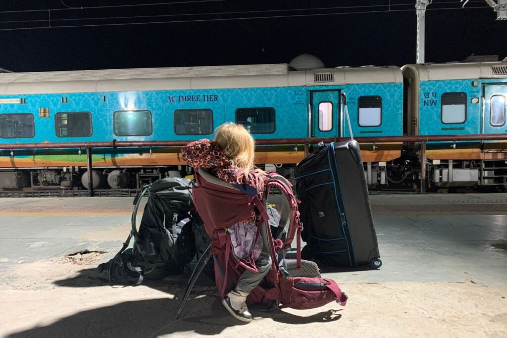 child in a backpack at a train station