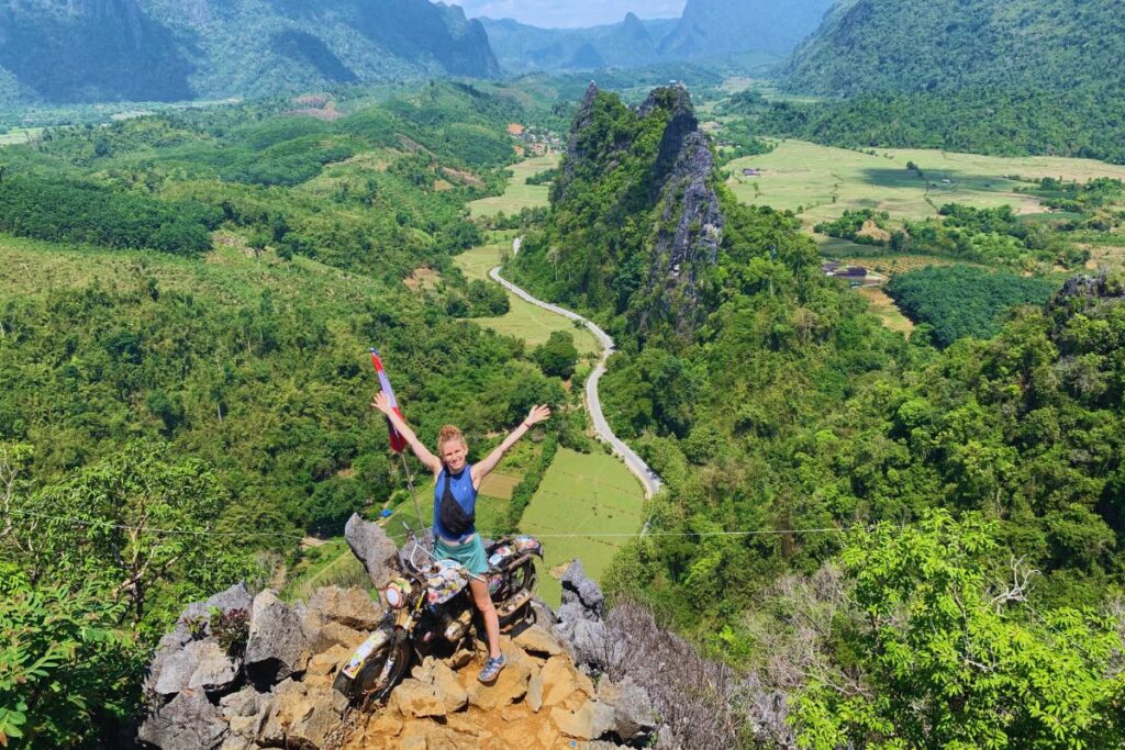 woman sitting on a motorcycle on top of a mountain with scenic views