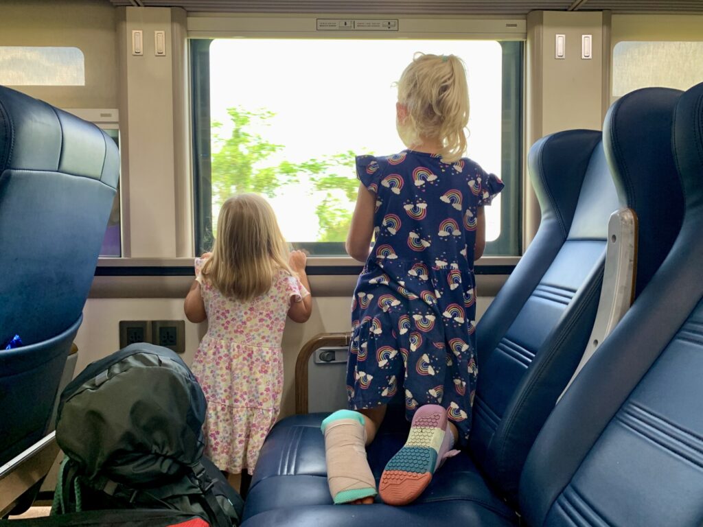 two girls looking out a window on a train