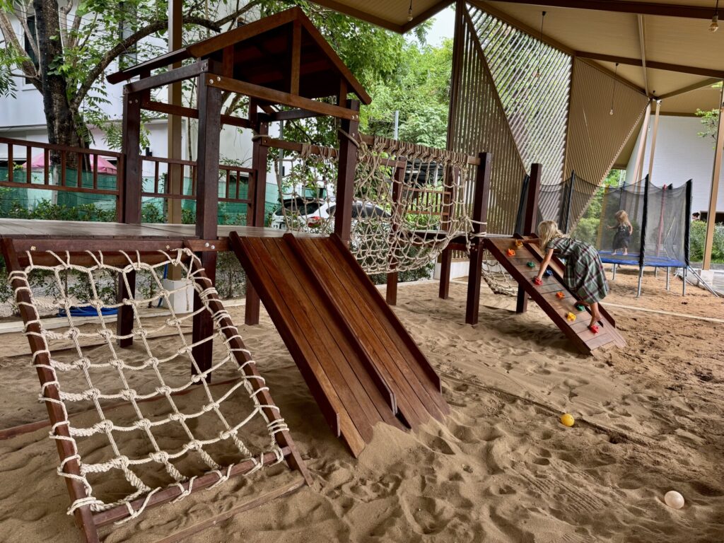 wooden playground and sand pit with a trampoline