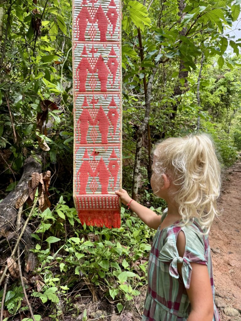 girl touching a red patterned marker in a jungle