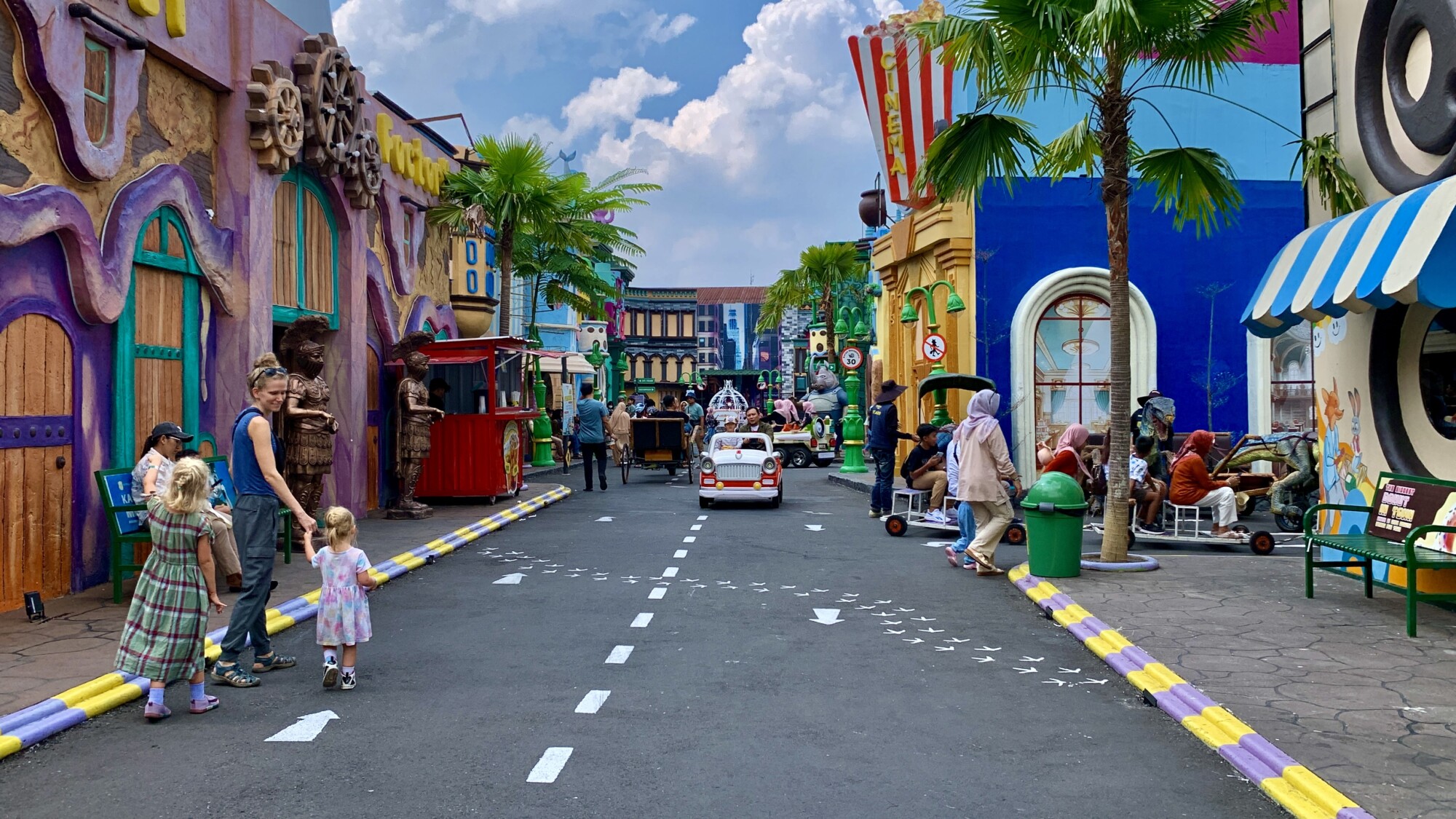 people walking the streets of a theme park with colorful cartoon style buildings