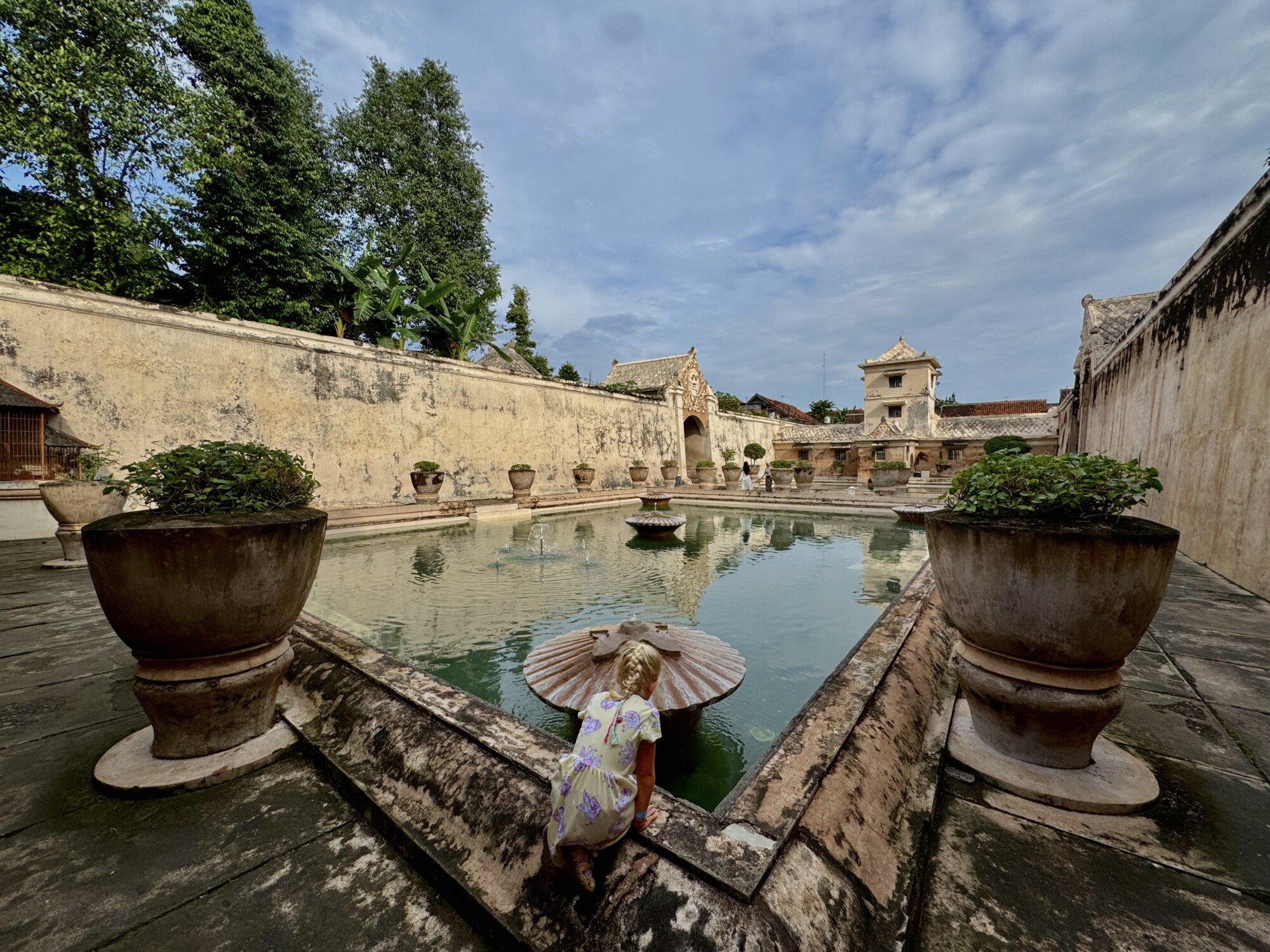 a girl reaching in the water of a royal bath