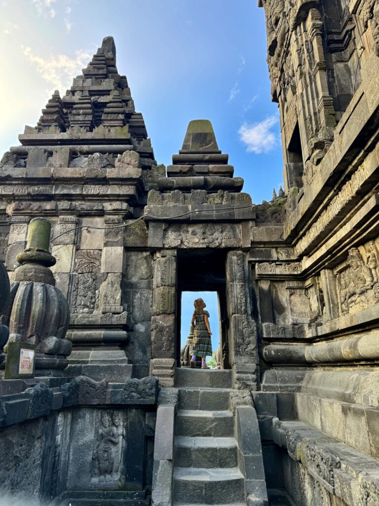 a girl in a doorway looking at the carvings on the wall at a Hindu temple