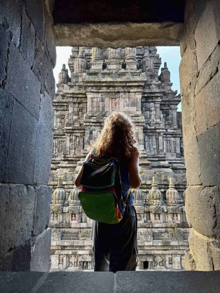 a woman standing in a stone window looking out at a temple