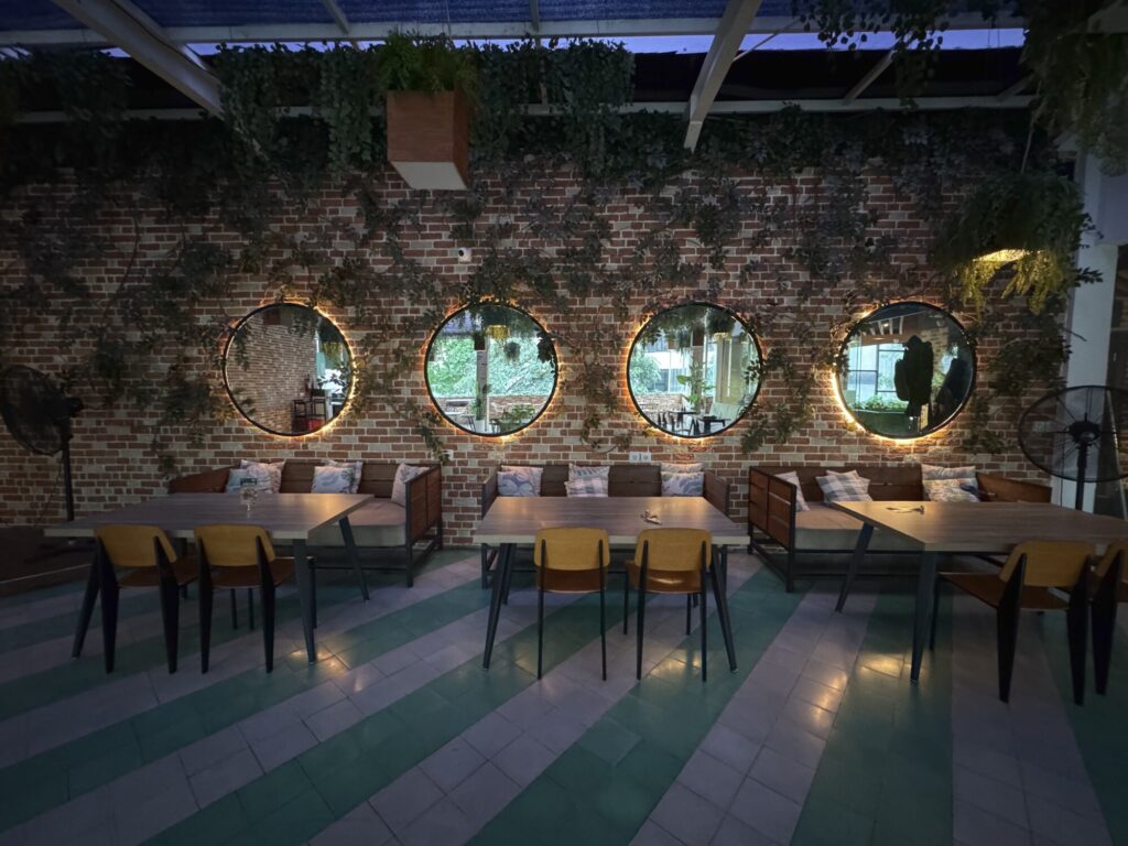 four mirrored lights and 3 tables with a brick and vine wall