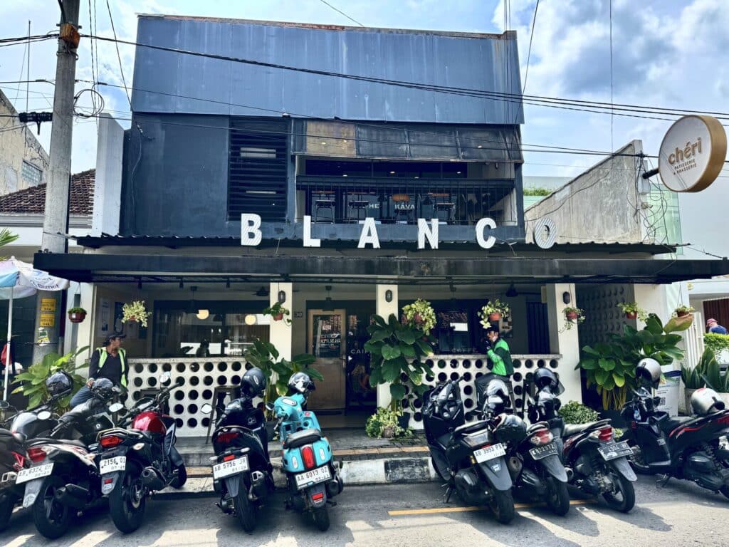 outdoor sign of a coffee shop with motor bikes parked out front