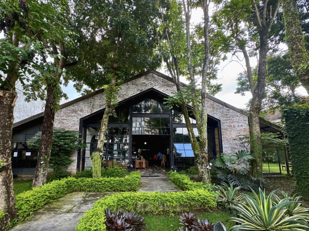 warehouse style building with trees and a bush lined walkway