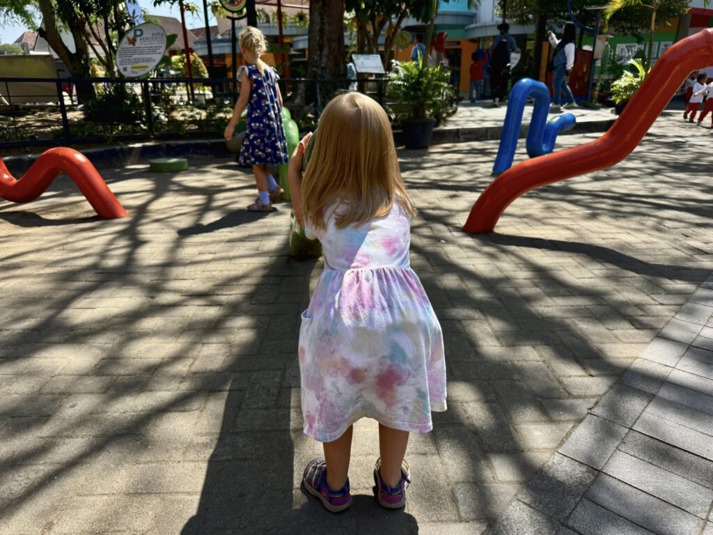 two girls at an outdoor play space with colorful outdoor equipment