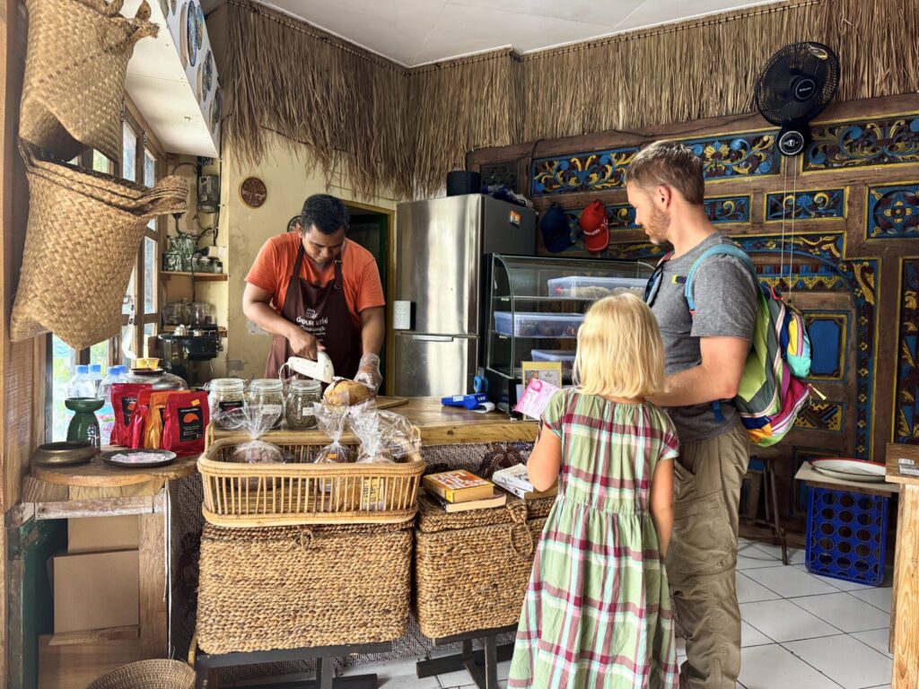 person cutting a loaf of sourdough bread while two people watch