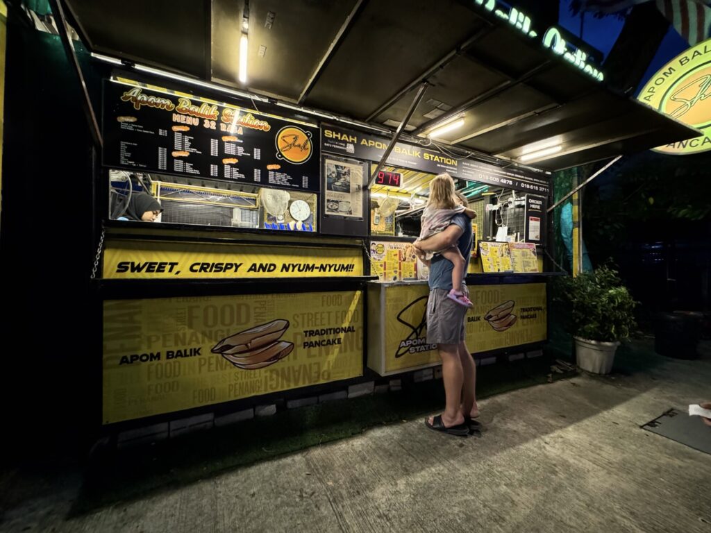 father holding daughter outside of a food stall
