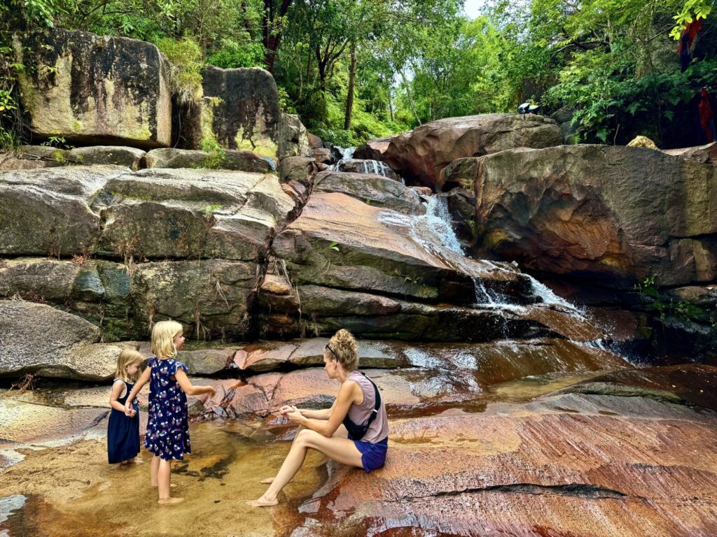 family with two girls and a mother playing at a waterfall in a jungle