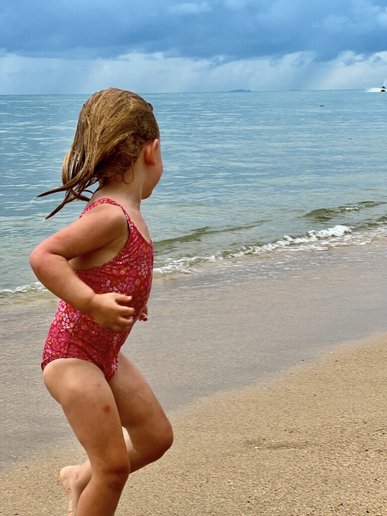 girl in a pink swimsuit running on a beach