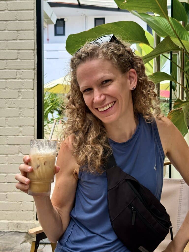 woman smiling holding an iced coffee