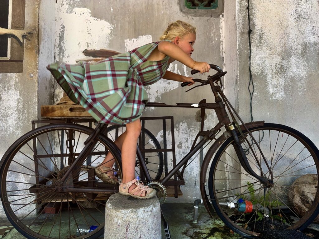 girl with dress blowing as she is acting like she is riding a vintage bicycle quickly