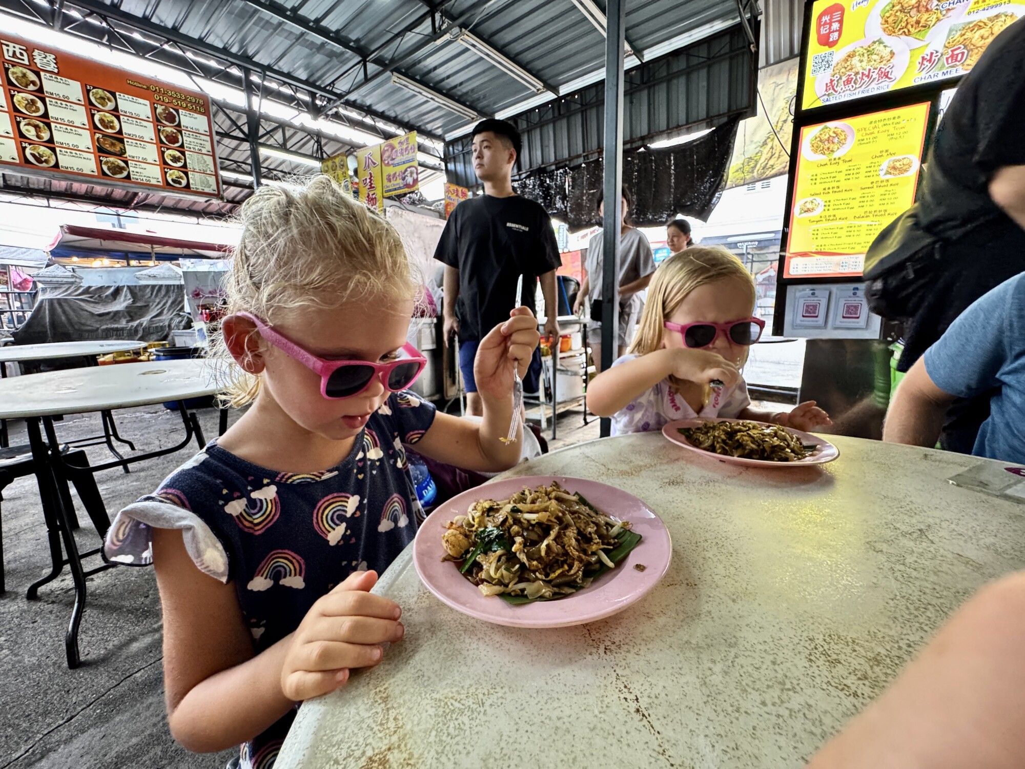 two kids eating at a street food vendor stall