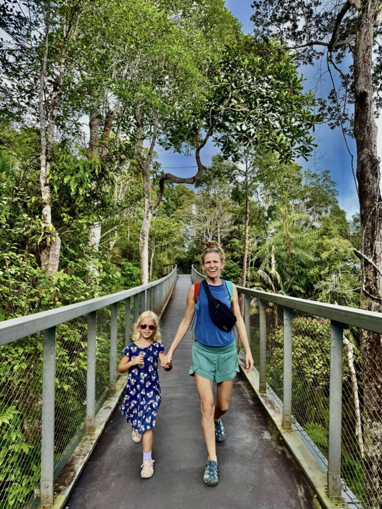girl and mother walking on a suspension bridge over the jungle canopy