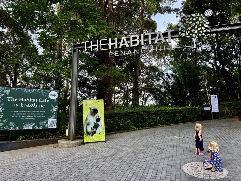 the habitat at penang hill sign with two kids playing under it