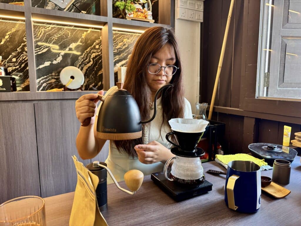 a person pouring hot water to make drip coffee for a customer