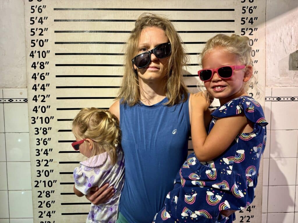 a mother posing like a mugshot holding two children