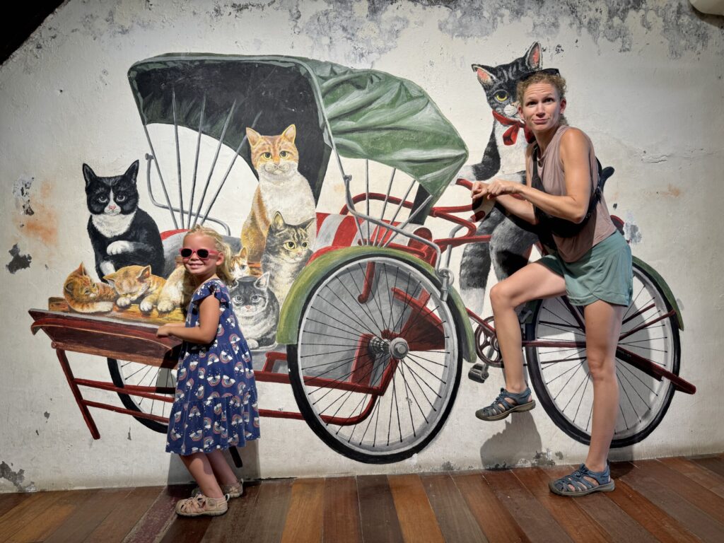 a mom and a girl interacting with a cat street mural