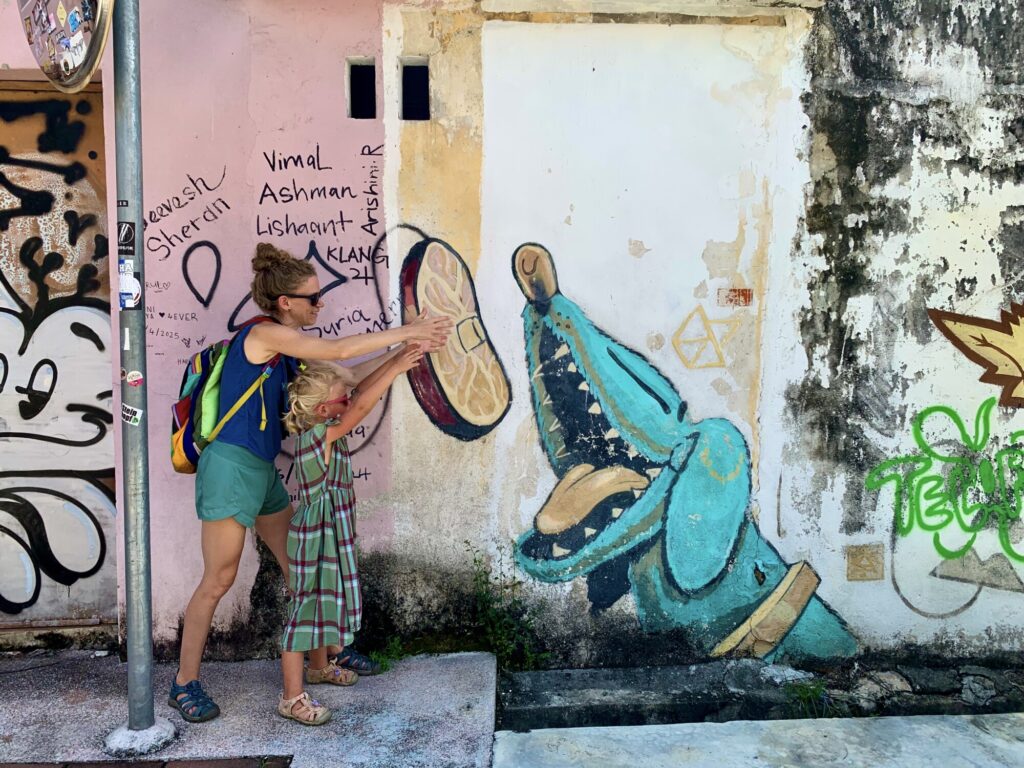 a mom and girl interacting with a street mural feeding a dog a steak
