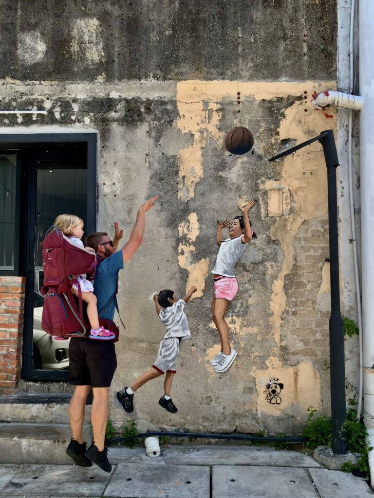 interactive street art with a man shooting a basketball over two girls