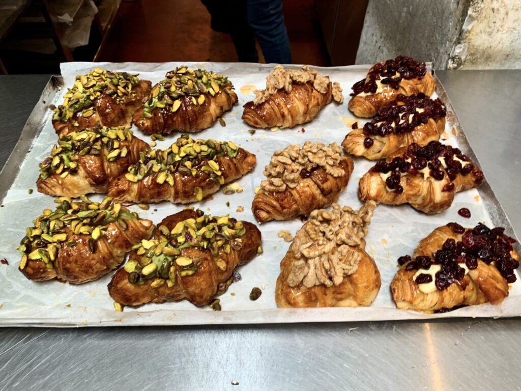 multiple pastries with different toppings and croissants