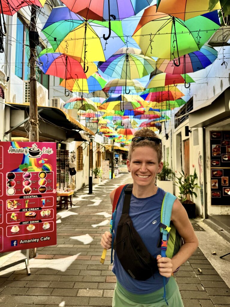 colorful umbrellas over a street with a woman posing