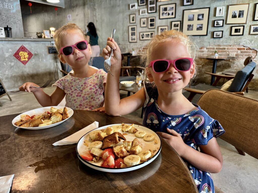 two girls eating french toast with fruit at a cafe