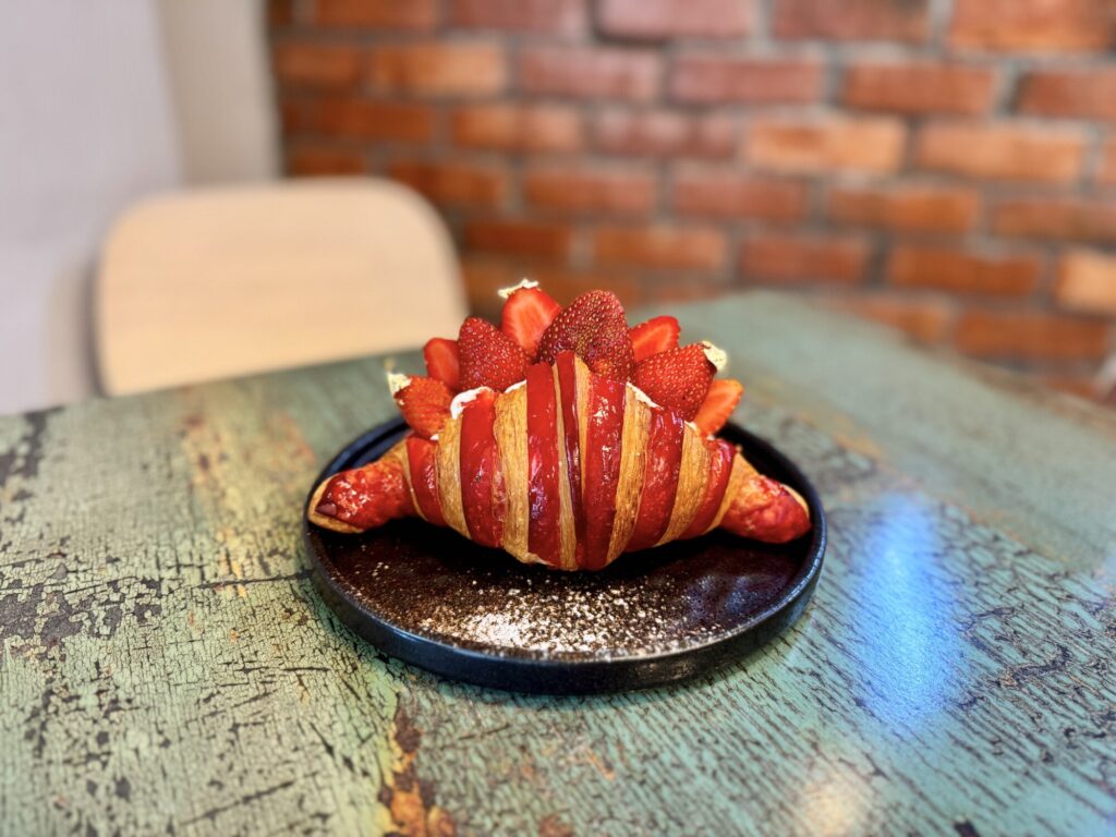 a croissant that looks like a dinosaur with cut strawberries
