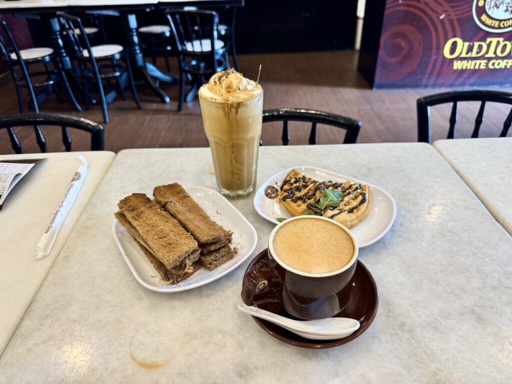 Iced coffee with toast, waffle, and hot coffee on a table