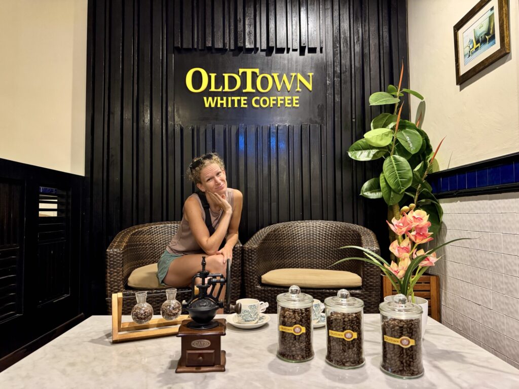 woman posing in front of a cafe sign with coffee beans displayed on a table