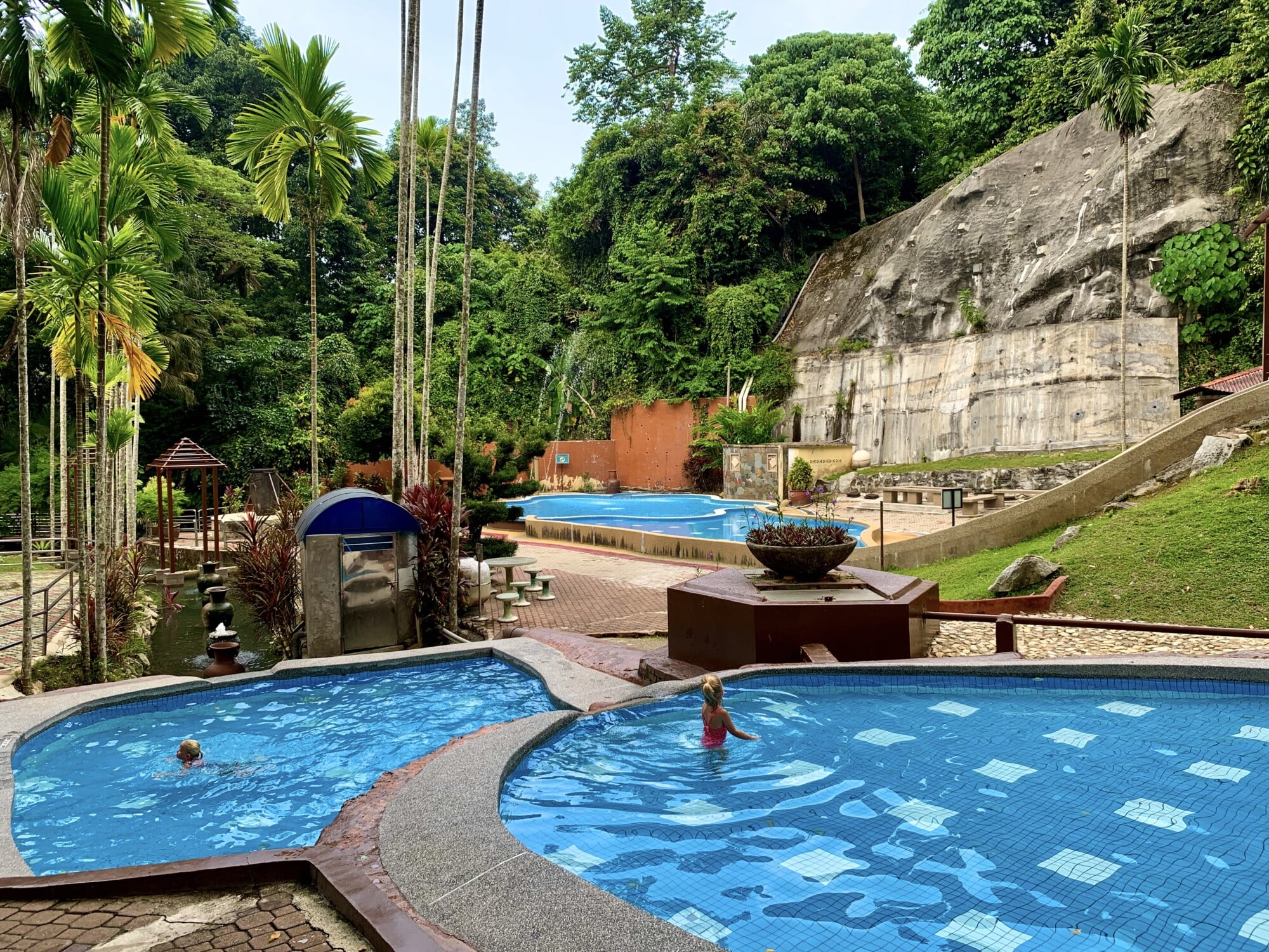 multiple outdoor swimming pools with kids playing in the pool