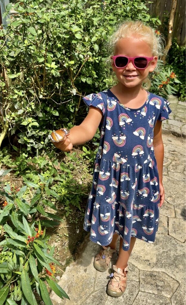 a girl who is happy as a butterfly landed on her finger