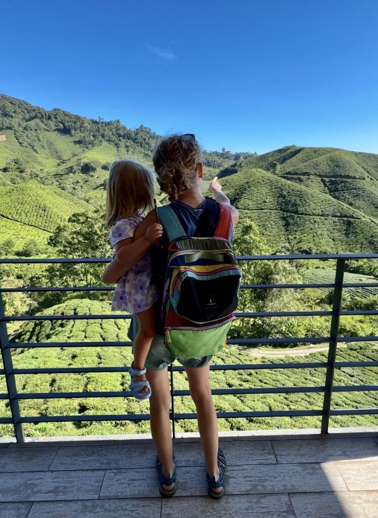 a mom and a daughter looking out to a tea plantation with rolling hills