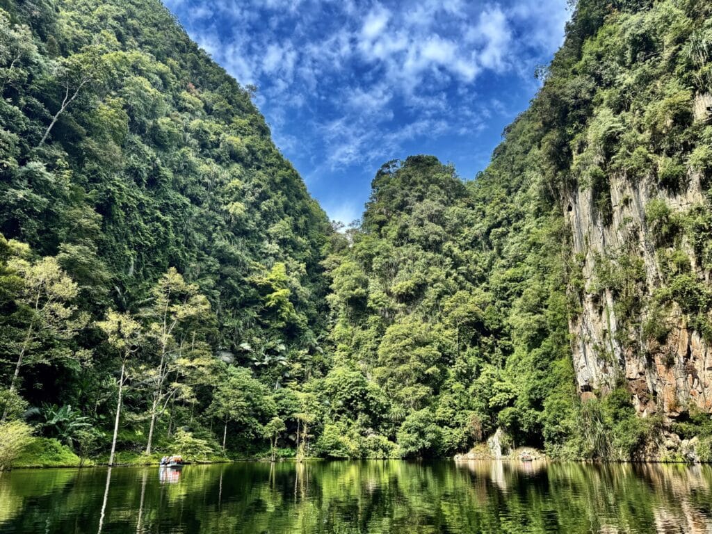 boat on calm water lake with limestone cliffs towering over the lake