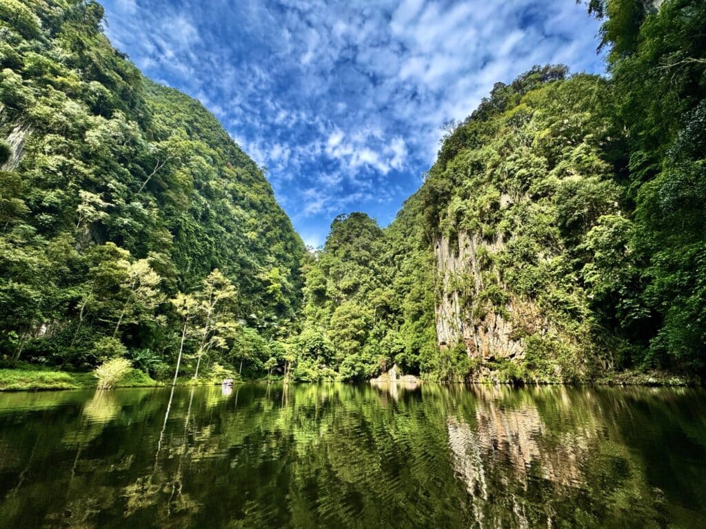 lake with surrounding limestone cliffs and blue sky with white clouds