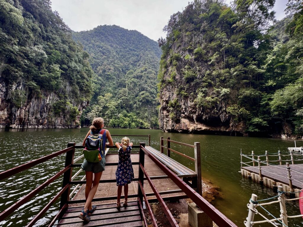 a mom and a daughter on a viewing platform looking at a lake surrounded by limestone cliffs