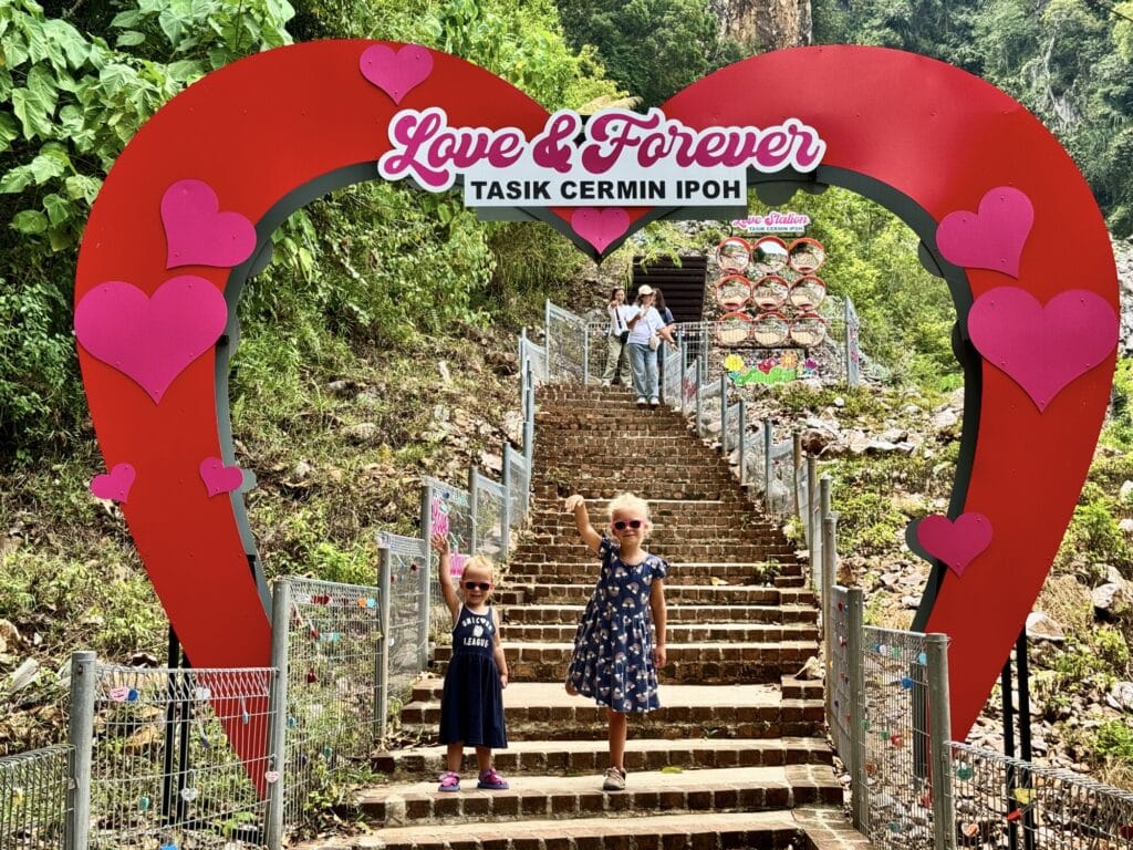 two girls posing under a heart sign