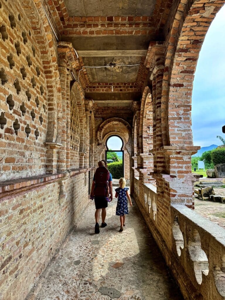 dad with his two girls walking in an outside corridor with brick and arches
