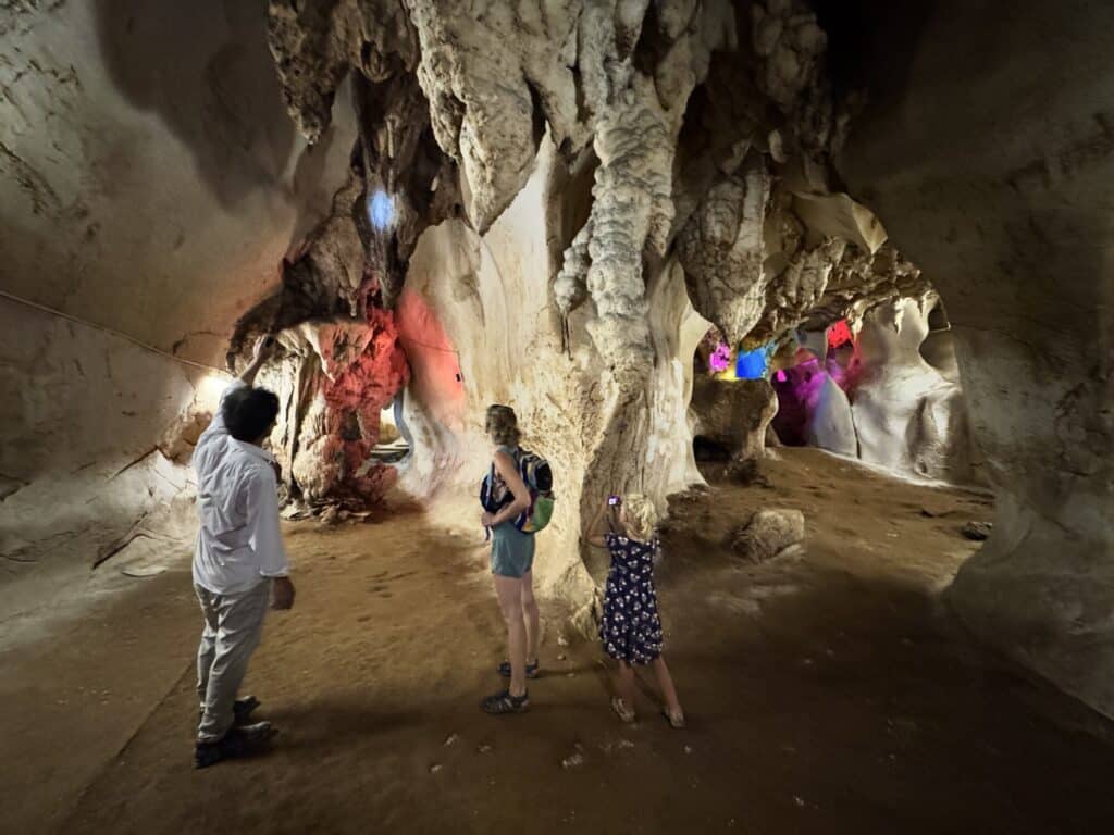 a man taking a woman and a child on a tour in a cave