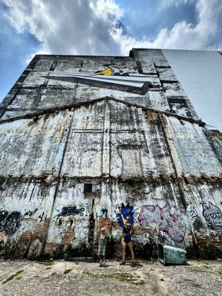 large side of a building with street mural of two kids in a paper airplane