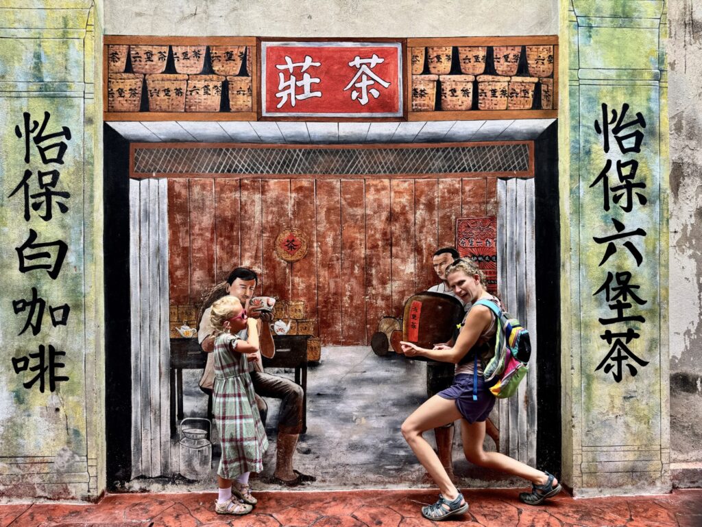 a woman and a girl posing in a silly way in front of an interactive street mural