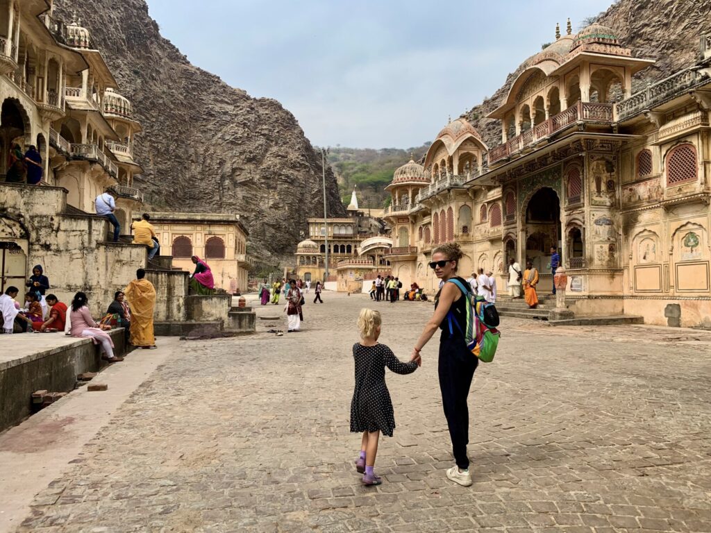 woman and child walking around a temple between two cliffs