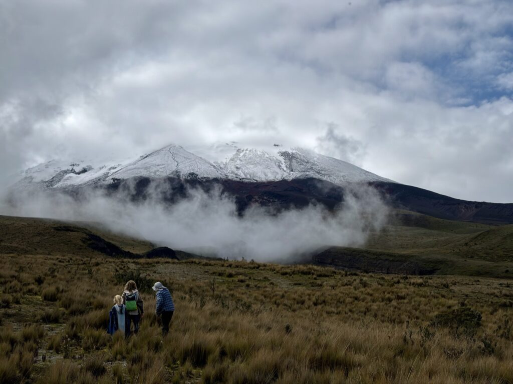 three people looking at a volcano covered in clouds