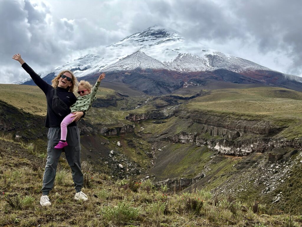 woman and child posing in front of a snow covered volcano with a canyon in the mid ground