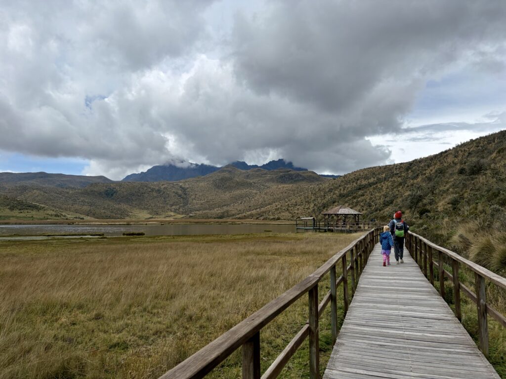 people walking on a wooden walkway at the edge of a lagoon